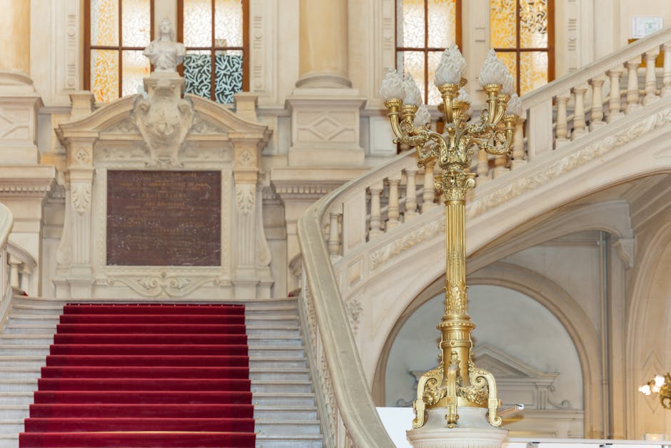 Elegant grand staircase with red carpet and ornate lamp post